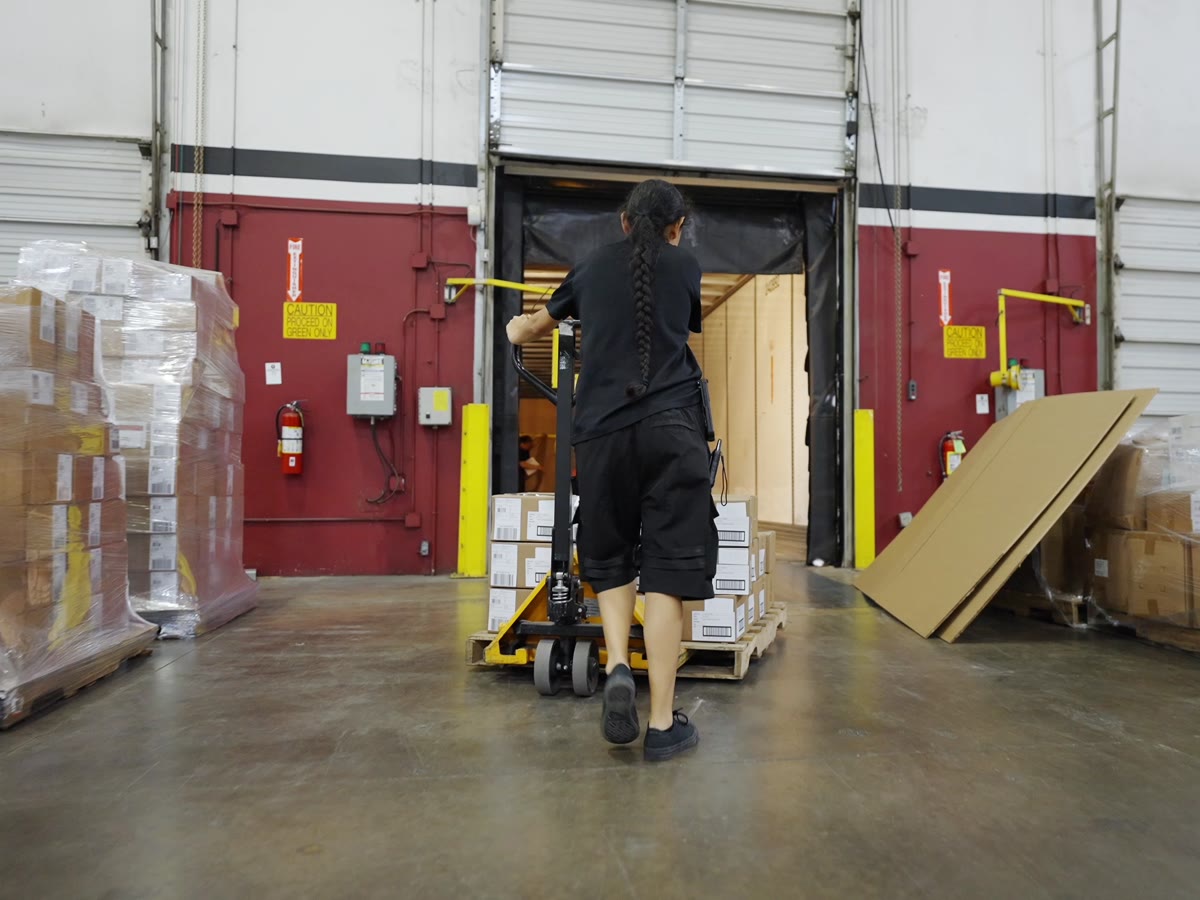 A Productiv operator moving a pallet of cartons through a dock door into a waiting trailer